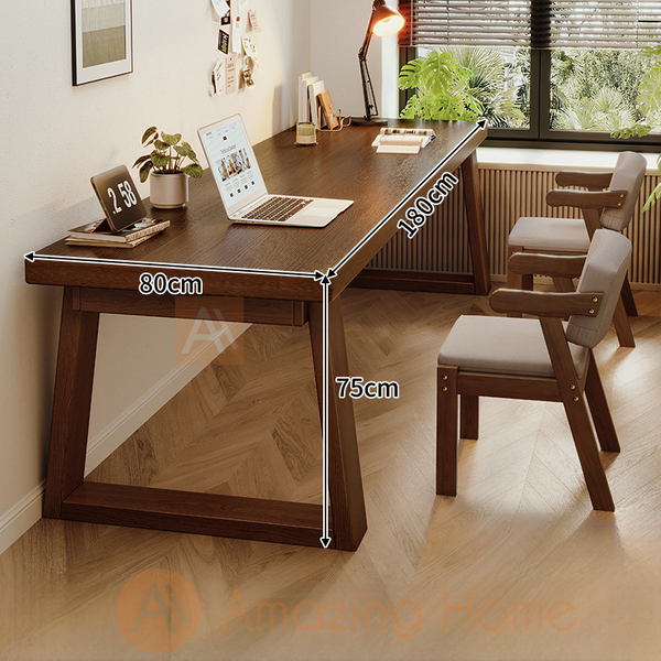 A two-person solid wood working desk with wide legs and two chairs set, in a home office setting.